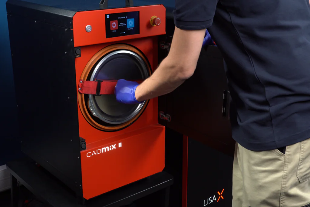 Operator using CADmix II powder mixer to prepare reused MJF PA12 material for SLS 3D printing, next to a Lisa X printer.