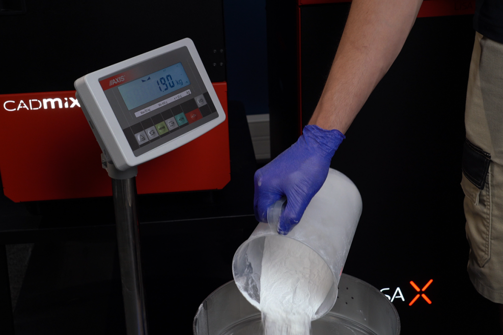 Operator pouring MJF PA12 powder onto a scale for weighing before mixing in the CADmix II unit.